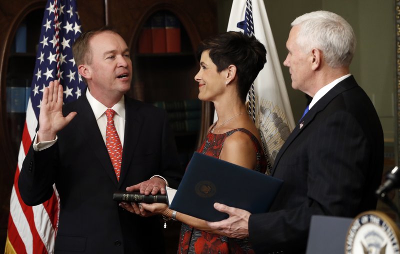 Vice President Mike Pence swears in Mick Mulvaney as Director of Office of Management and Budget in the White House complex in Washington, Thursday, Feb. 16, 2017, as Pamela West Mulvaney holds the Bible. 