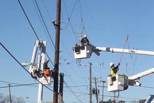 The Sentinel-Record/Richard Rasmussen POLE DAMAGED: Entergy Arkansas Inc. linemen work to restore power in the 100 block of Albert Pike Road near Anna Street intersection Thursday after a van struck a utility pole following a chase earlier in the morning.