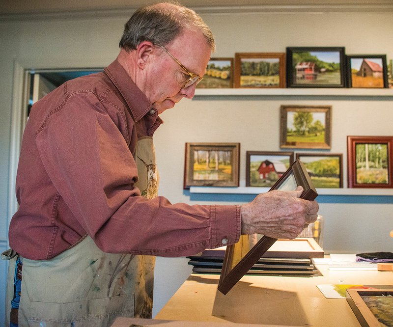 Bud Finley of Alexander inserts one of his paintings into a frame as he gets ready to attend the ninth annual Delta Visual Arts Show in Newport, which will take place Saturday. A sampling of his artwork is shown on the wall behind him in his home studio.