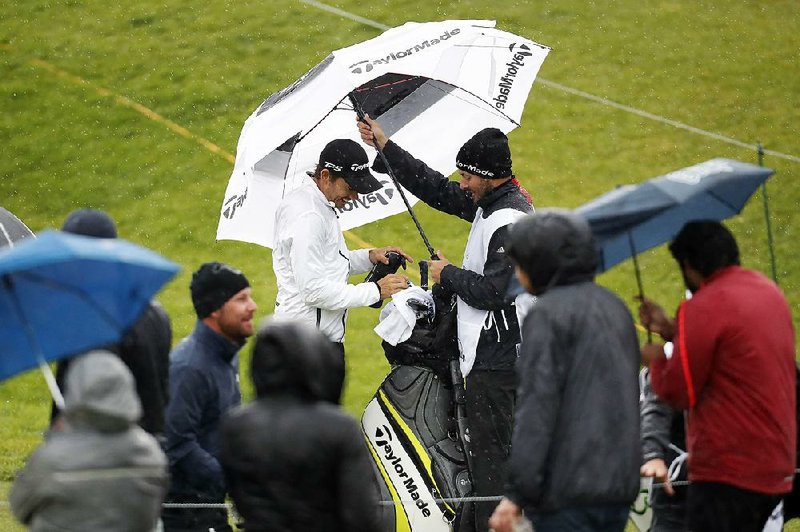 Camilo Villegas (left) puts his driver back in the bag on the 10th tee box after play was suspended Friday during the second round of the Genesis Open at Riviera Country Club in Los Angeles