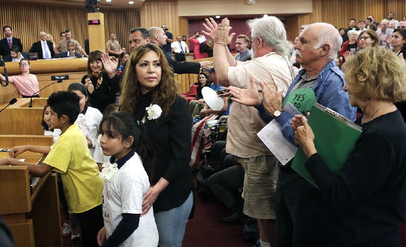 Nora Sandigo arrives to speak at Friday’s county commissioners meeting in Miami with several of the children under her legal guardianship, saying deportations had made “these kids … orphans.”