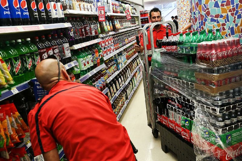 Employees deliver cases of Coca-Cola in October to a store in Miami Beach, Fla.