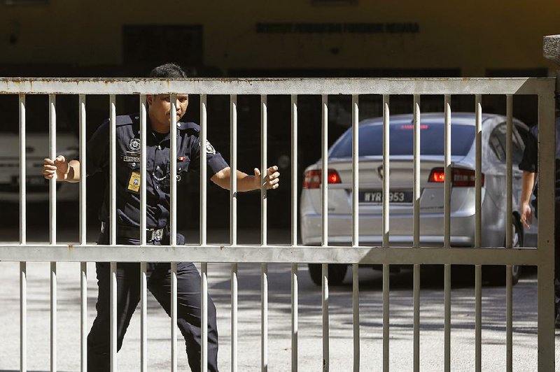 A police officer closes a gate Saturday outside the hospital in Kuala Lumpur, Malaysia, where a second autopsy was to be performed on North Korean Kim Jong Nam.