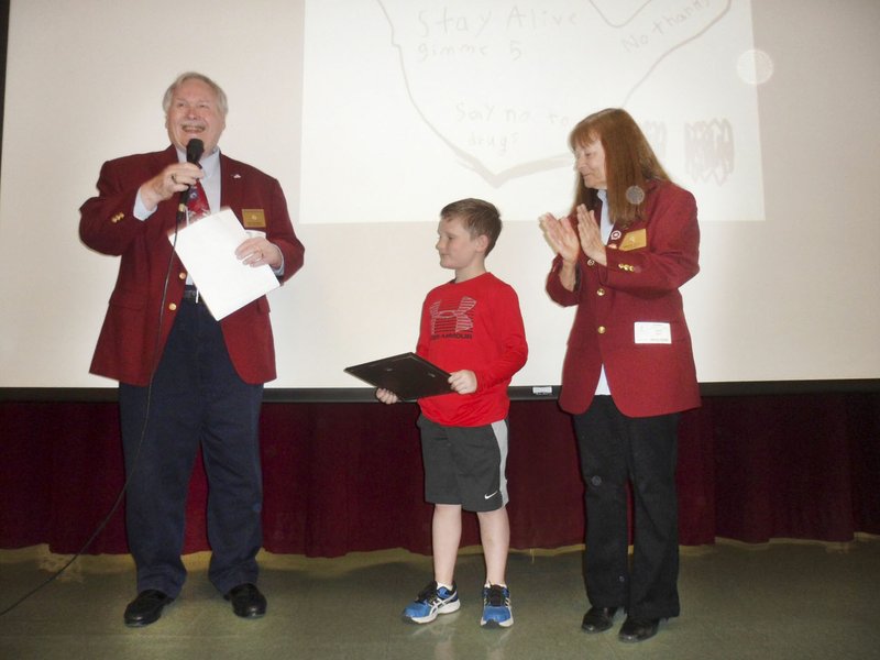 Fayetteville-Springdale Elks Lodge held a drug awareness poster contest among six school districts in Northwest Arkansas, and the third-grade winner, Caleb Baker, received a certificate and had his poster projected on a screen before the entire Holcomb Elementary School assembly. Pictured are Ron Materna (from left), lodge officer; Baker; and Marge Guist, lodge officer.