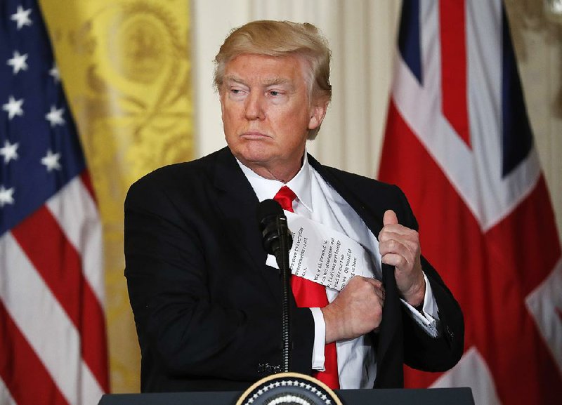 President Donald Trump tucks away his notes near the conclusion of a joint news conference with British Prime Minister Theresa May in the East Room of the White House White House in Washington, Friday, Jan. 27, 2017. 