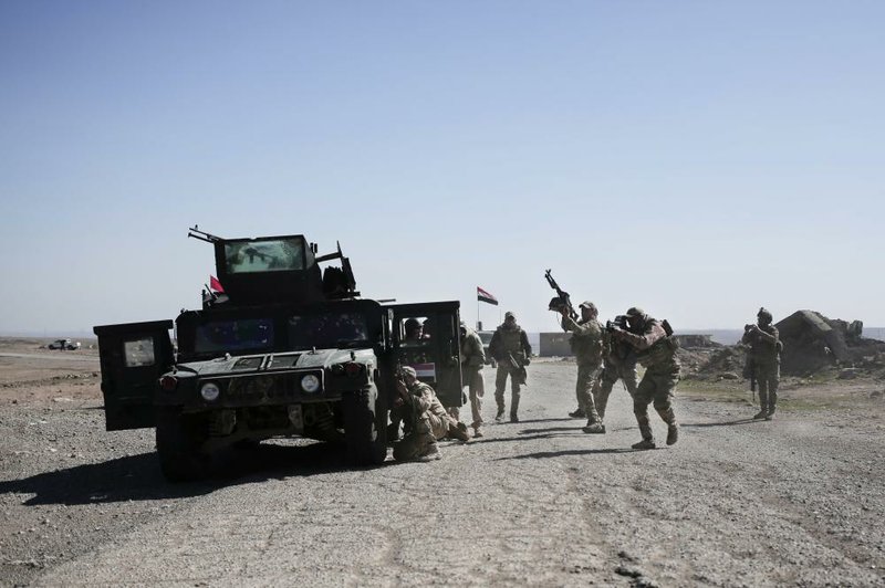 Iraqi police forces fire on Islamic State militant positions from a hillside near the town of Abu Saif on Monday.