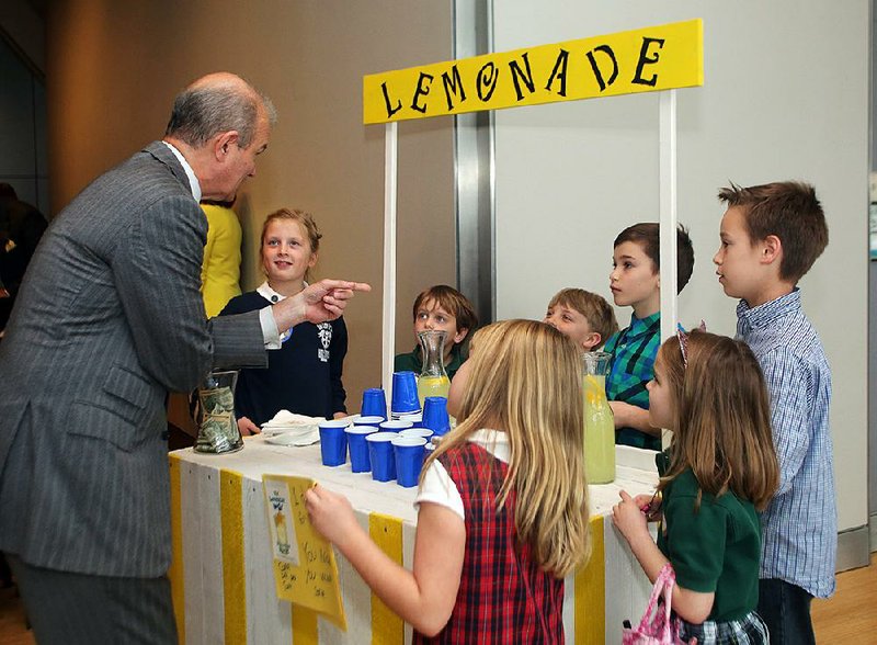 Rotarian Kenny Gibbs (left) talks to the children of other Rotarians about the book The Lemonade War as the children sell lemonade at the Clinton Presidential Center in Little Rock on Tuesday.