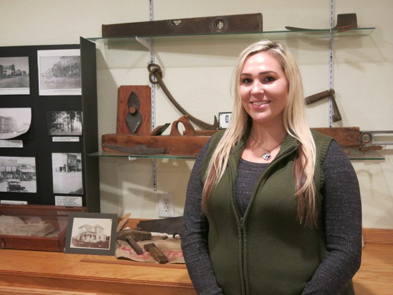 Photo by Susan Holland Randi Van Noy posed beside a display of antique carpenter&#8217;s tools and farm implements, one of the exhibits in the Gravette historical museum annex building. Van Noy is the new museum curator and is busy lining up exhibitors for the &#8220;My Collections&#8221; show in April. She will be keeping the museum open and giving tours from 10 a.m. to 3 p.m. Thursdays, Fridays and Saturdays.