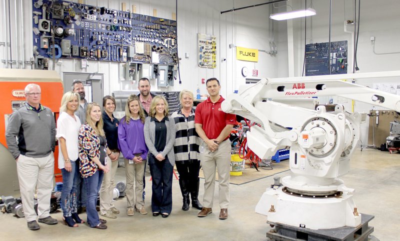 Michael Burchfiel/Herald-Leader Tyson employees stood next to the palletizer robot that was donated to the Career Academy of Siloam Springs.