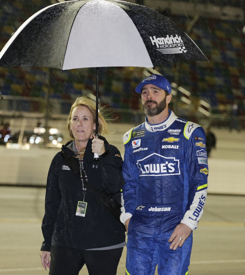 Jimmie Johnson, right, takes shelter under an umbrella with a team member during a rain delay before the NASCAR Clash auto race at Daytona International Speedway, Saturday, Feb. 18, 2017, in Daytona Beach, Fla. (AP Photo/Terry Renna)