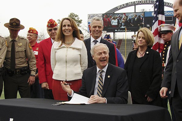 Arkansas Gov. Asa Hutchinson signs a bill on the field at War Memorial Stadium on Wednesday, Feb. 22, 2017, in Little Rock placing the stadium under the control of the state Parks and Tourism Department. 