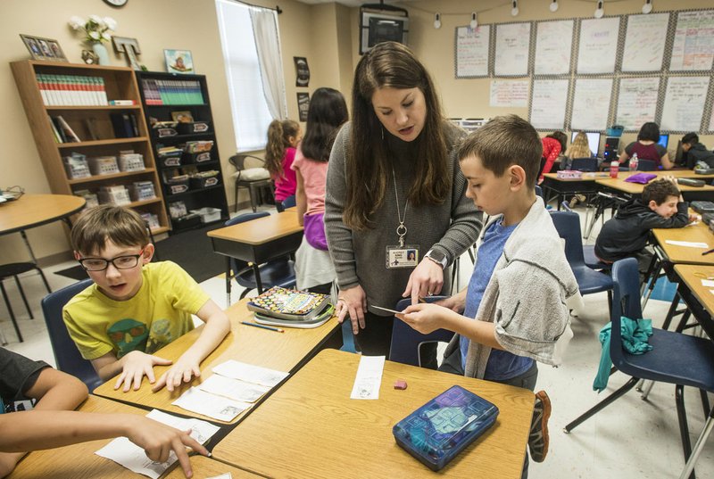 Audrey King, fourth-grade teacher at Tucker Elementary School, helps Michael Girenko, 9, with his assignment Tuesday at the Rogers district school in Lowell. 