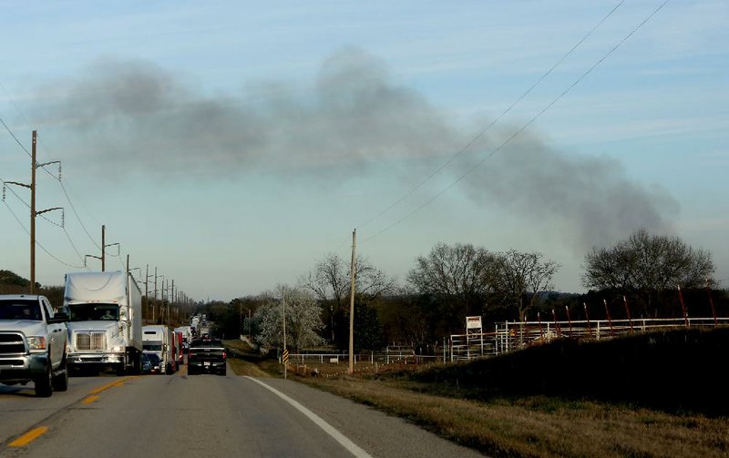 Smoke from a tractor-trailer wreck rises near traffic Wednesday on U.S. 64 outside Mulberry in Franklin County. The driver of the tractor-trailer died after the vehicle, which was hauling 40,000 pounds of ammunition, caught fire on Interstate 40.