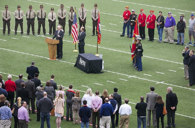 Gov. Asa Hutchinson (at lectern) signs three government reorganization bills Wednesday at War Memorial Stadium, including one to put the War Memorial Stadium Commission under control of the state Department of Parks and Tourism.