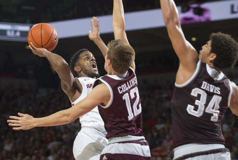 Arkansas guard Daryl Macon (4) gets off a shot over the defense of Texas A&M guard Chris Collins (12) and center Tyler Davis (34) on Wednesday, Feb. 22, 2017, at Bud Walton Arena in Fayetteville.