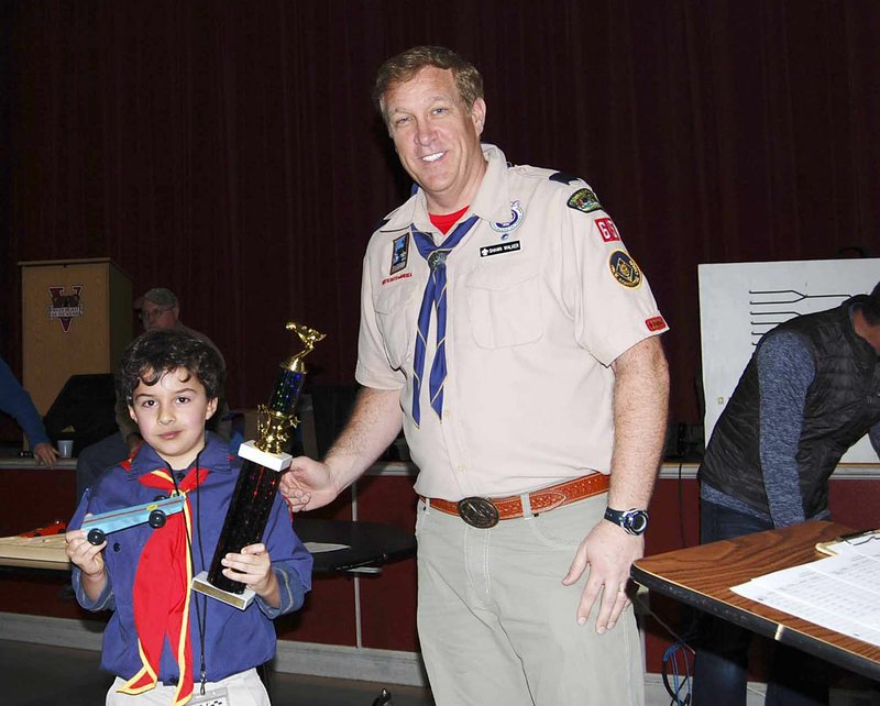 Courtesy photo Shawn Walker, leader of Cub Scout Pack 65, awards the grand champion tropy to Cub Scout Nat Dafashy for the pack's Pinewood Derby on Jan. 22 at Vandergriff Elementary School in Fayetteville.