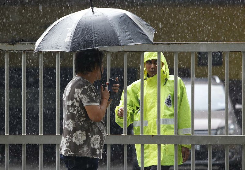 A Malaysian police officer talks to a woman Friday outside the forensic department at the Kuala Lumpur hospital.