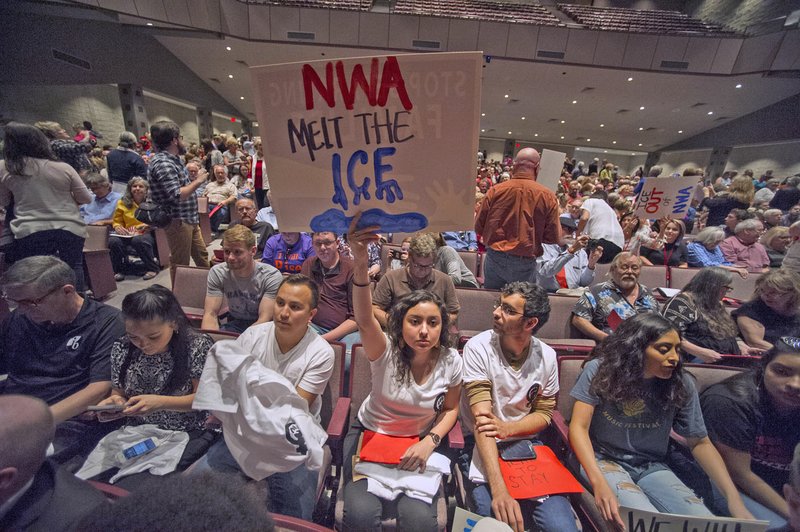 Jacqueline Perez of Springdale holds a sign Wednesday at a town hall meeting held by Sen. Tom Cotton, R-Ark., at Springdale High School’s Pat Walker Performing Arts Center.