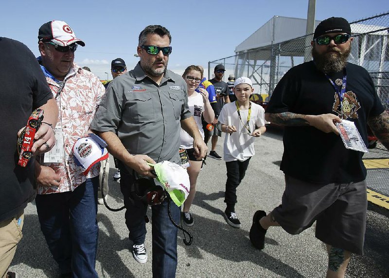 Car owner Tony Stewart, center, is surrounded by fans seeking autographs as he walks through the garages at a NASCAR auto racing practice session at Daytona International Speedway, Friday, Feb. 24, 2017, in Daytona Beach, Fla. 