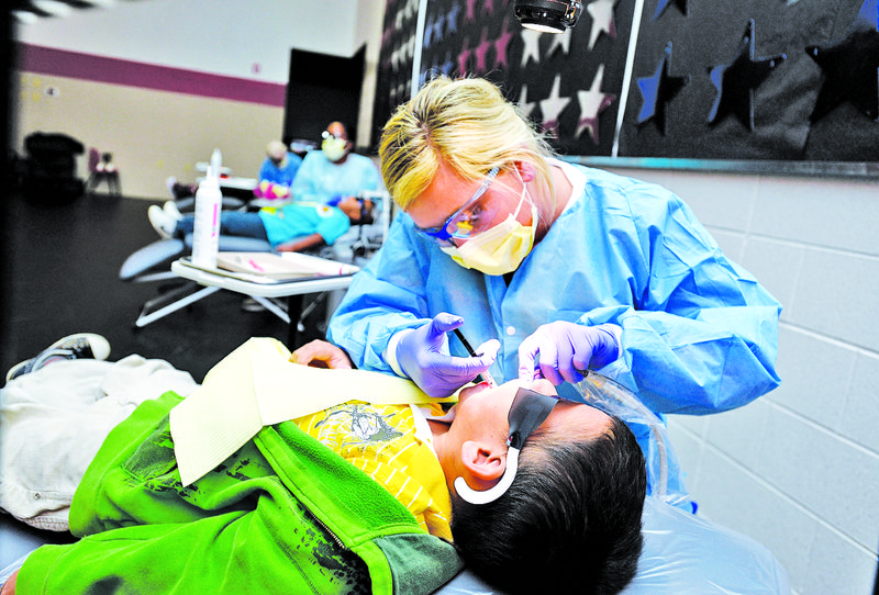 In this 2015 file photo, Lexi Johnson, dental hygienist with Arkansas Children's Hospital, applies dental sealants to Benito Frausto, 8, second-grader at Sonora Elementary School in Springdale.