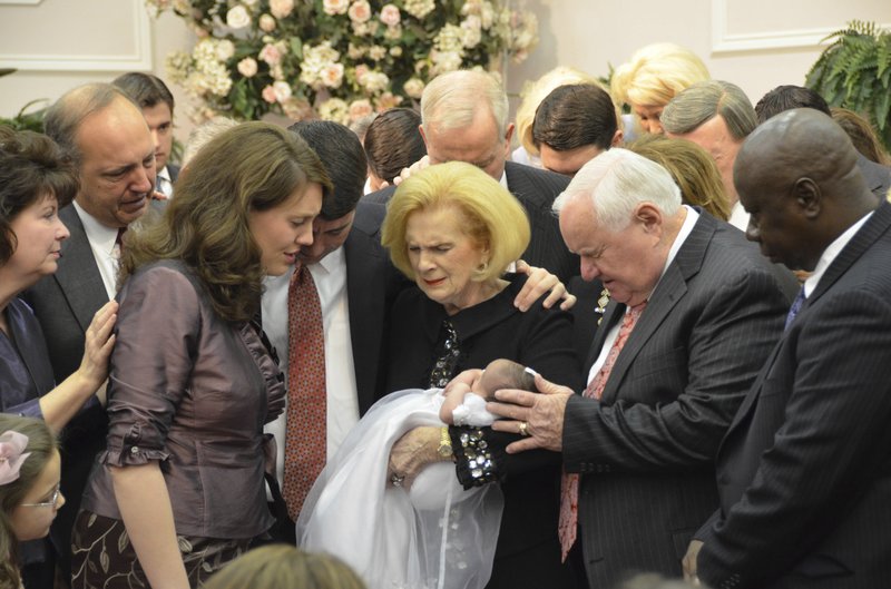 In this 2012 provided by a former member of the church, Word of Faith Fellowship leader Jane Whaley, center, holds a baby, accompanied by her husband, Sam, center right, and others during a ceremony in the church's compound in Spindale, N.C. 