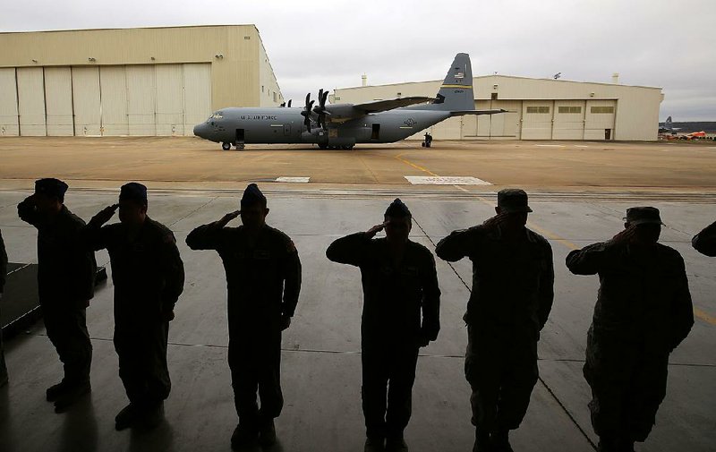 Crew members salute as Maj. Gen. James Hecker (not pictured) approaches the stage at the start of a ceremony to celebrate the delivery of a new C-130J aircraft (background) on Monday at Little Rock Air Force Base in Jacksonville.