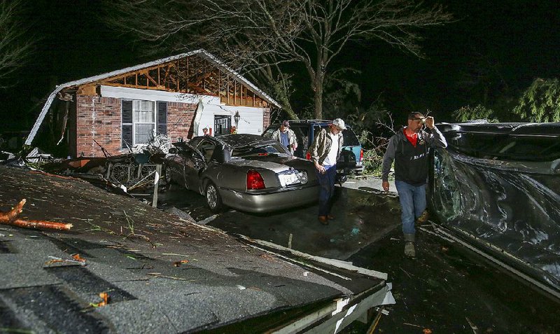Members of a family deal with a detached roof and an overturned vehicle (right) Tuesday night on Holiday Terrace in the White County town of Higginson after a strong storm passed through.
