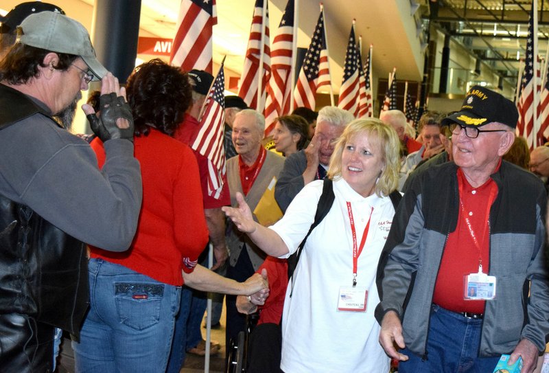 Photo by Mike Eckels A Vietnam War veteran (far left), salutes a comrade in arms from the Korean Conflict in one of the touching moments of the welcome home ceremony for the 2016 Honor Flight at Northwest Arkansas Regional Airport in Highfill April 20, 2016.