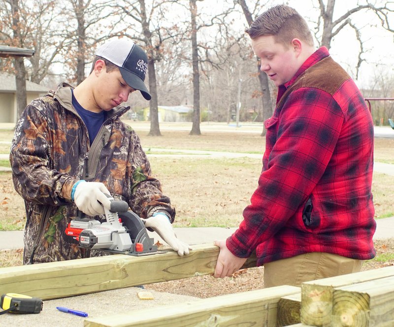 Photo by Randy Moll Miley McMillan and Dalton Evans, FFA officers and sophomores at Gentry High School, were at work cutting out the pieces for a corn hole toss game the FFA was constructing in the horseshoe area of Gentry City Park on Friday, Feb. 24, 2017.