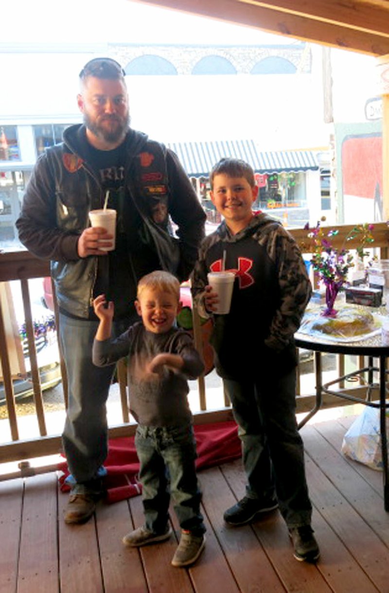 Photo by Susan Holland Jason Rodden, a member of the Sons of Inferno motorcycle club, and his sons, Jacob, 4, and Isaac Wilf, 12, were among those who attended the club&#8217;s Mardi Gras party Saturday night. Jason was manning the donation table on the front deck at Fire Station 29 and Jacob was having a good time waving to the camera.