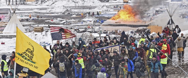 In this Feb. 22, 2017, file photo, a fire set by protesters burns in the background as opponents of the Dakota Access pipeline leave their main protest camp Wednesday near Cannon Ball, N.D. 