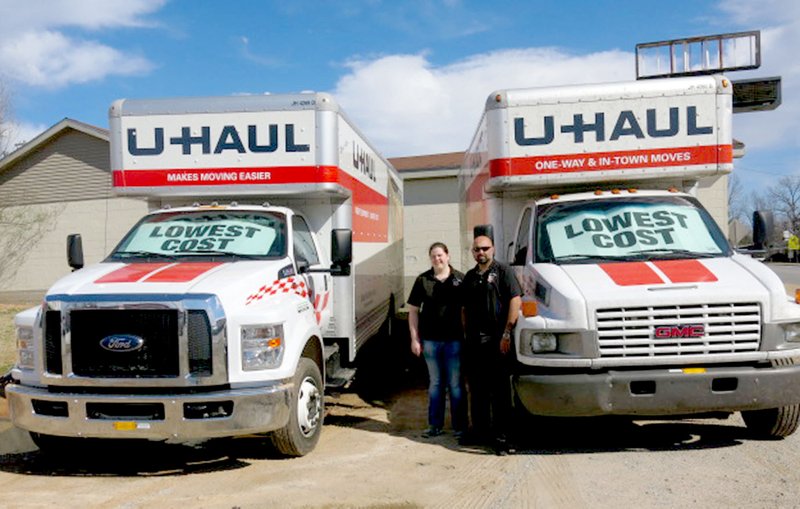Erin and Ricky Sehgal, owners of the Gravette Station, posed last week with a couple of the large U-Haul trucks that are available for rental at the station. Erin Sehgal and her brother, Benjamin Brewer, signed on as U-Haul neighborhood dealers in December and will offer U-Haul trucks and trailers, towing equipment, support rental items and in-store pickup for boxes.