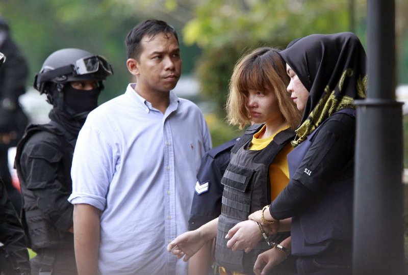 Vietnamese suspect Doan Thi Huong (second from right), is escorted out of court Wednesday in Sepang, Malaysia, where she was charged with murder.