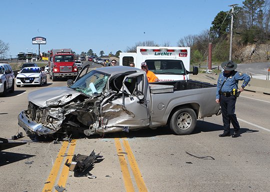 The Sentinel-Record/Richard Rasmussen DAMAGED TRUCK: An Arkansas state trooper examines the remains of a Chevrolet Colorado pickup truck that reportedly crossed the centerline and collided with a tractor-trailer rig, causing it to overturn on the south shore bridge over Lake Hamilton in the 5200 block of Central Avenue at around noon Thursday.