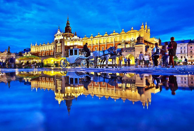 A rain puddle reflects the floodlit charm of Cloth Hall, one of several major buildings on Krakow’s Main Market Square.