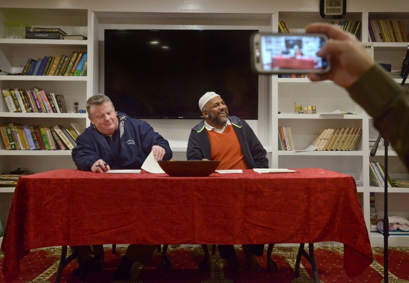 Scott Comiskey (left), senior warden at All Saints’ Episcopal Church in Bentonville, and Muhammad Khan, president of the Bentonville Islamic Center, sign a Letter of Understanding during a ceremony Feb. 2 at the mosque. The letter outlined an agreement between the two faith groups to build the Abrahamic Interfaith Center that would serve both.
