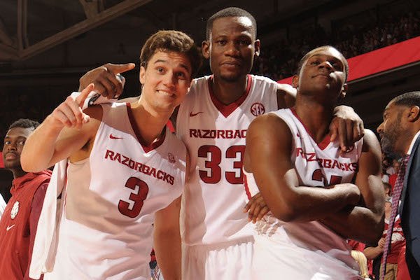 Arkansas seniors Dusty Hannahs (3), Moses Kingsley (33) and Manuale Watkins celebrate in the closing seconds against Georgia Saturday, March 4, 2017, during the second half of play in Bud Walton Arena in Fayetteville.