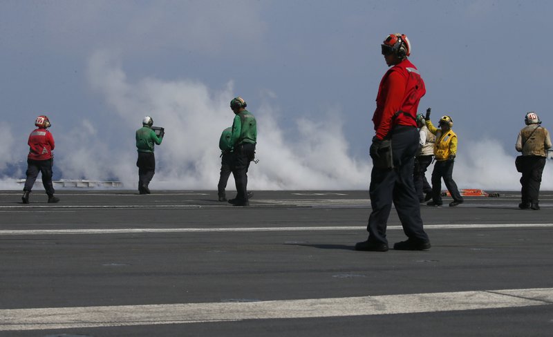 With smoke created by a F18 fighter jet taking off crewmen prepare the next one aboard the U.S. Navy aircraft carrier USS Carl Vinson (CVN 70) off the disputed South China Sea Friday, March 3, 2017. 