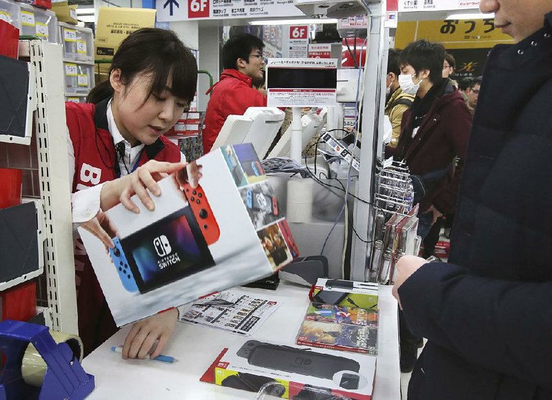An employee of electronics retailer Bic Camera sells Nintendo’s newest computer-game machine Switch in central Tokyo on Friday.