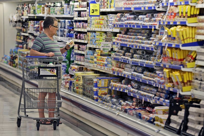 FILE - In this June 17, 2014, file photo, a shopper looks at an item in the dairy section of a Kroger grocery store in Richardson, Texas. Packaged food makers are trying to adapt their selling strategies as more people do their grocery shopping online. The worry is that products won&#x2019;t get as much exposure as in supermarkets, where shoppers have to walk past displays designed to trigger impulse buys. One way companies are trying to trigger impulse buys online is with targeted ads. (AP Photo/LM Otero, File)
