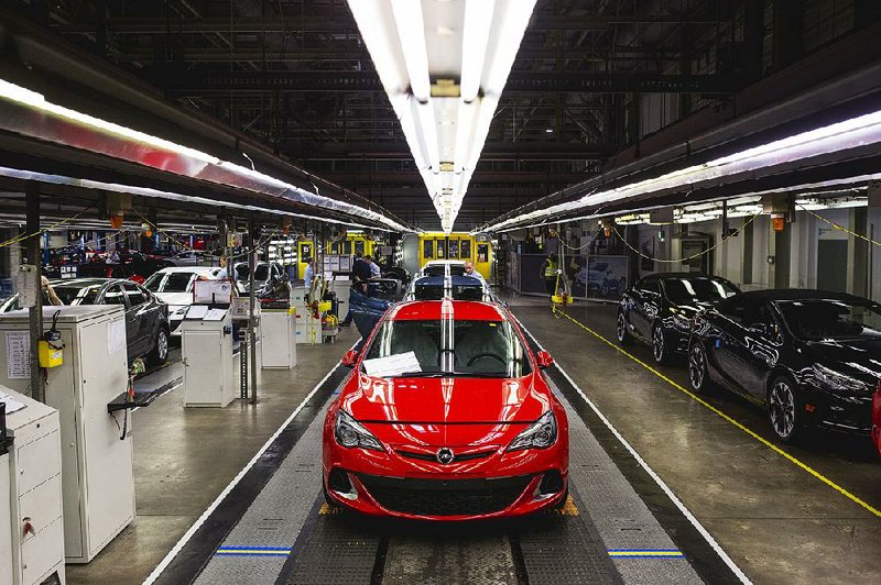 Workers inspect Opel Astra vehicles during quality control checks at the end of the production line at the Opel automobile plant in Gliwice, Poland, on Monday. The maker of Peugeot and Citroen cars will pay $2.2 billion for GM’s Opel unit and its U.K. sister brand Vauxhall.