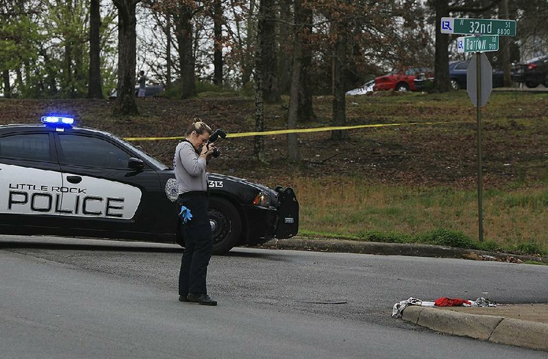 Little Rock Police Department crime scene investigator photographs the scene of a shooting Monday afternoon at West 32nd Street and Barrow Road. One person was critically injured in the shooting that occurred about 11:45 a.m.