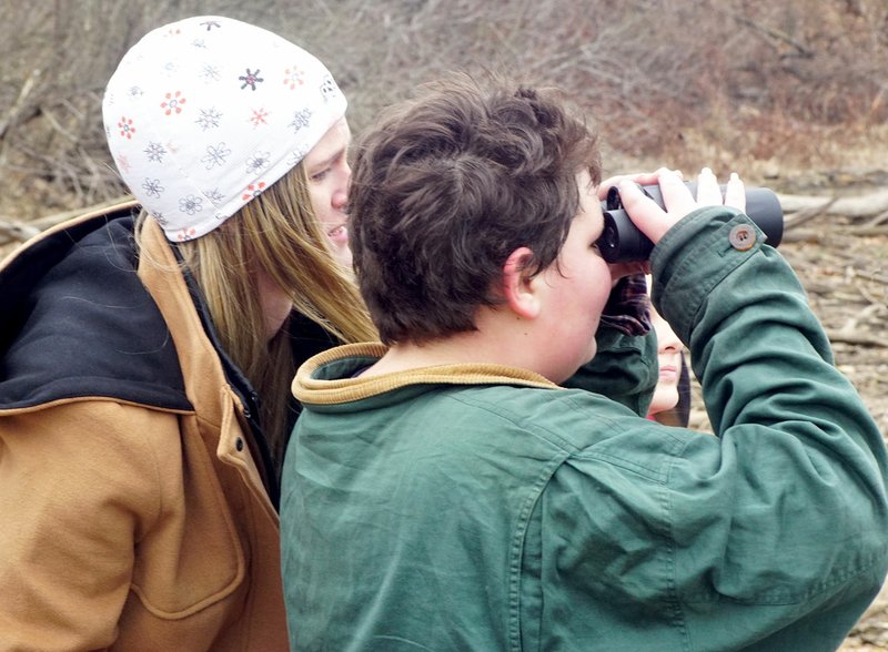 Photo by Randy Moll Jamie Johnson, science teach at Gentry Middle School, points out a bald eagle perched in a tree to Steele Edwards, with Kimberly Caswell in the background, during a sixth-grade science class field trip to Eagle Watch on Feb. 24.