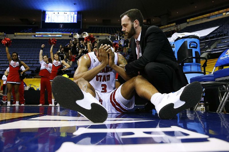 Arkansas State guard Devin Carter (left) is consoled on the baseline after the Red Wolves were upset by Louisiana-Monroe 73-70 in overtime during the first round of the Sun Belt Conference Tournament on Wednesday at Lakefront Arena in New Orleans.