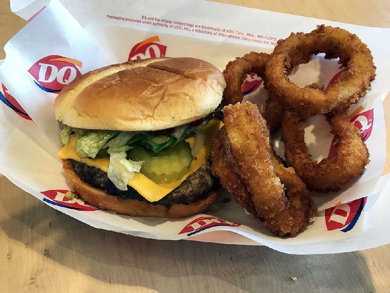 A Dairy Queen Cheeseburger is served here with onion rings — and undesired pickles. 