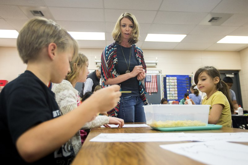 File Photo/NWA Democrat-Gazette Emilee Helmuth, Apple Glen Elementary School Global Connections teacher, talks with second-graders last month at the school in Bentonville. The school board is considering staff raises.