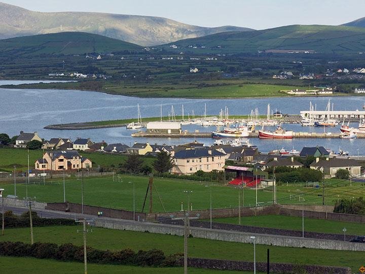 Boats float in the harbor against a backdrop of lush, rolling hills in Dingle, Ireland. The town on Ireland’s southwest coast has a lively pub scene.  