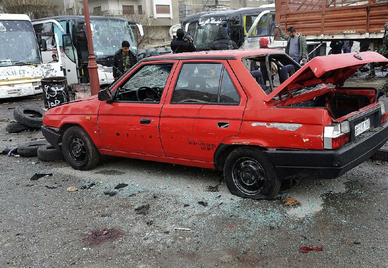 People inspect the damage Saturday at the site of two explosions in Damascus, Syria, in this photo released by the Syrian Arab News Agency.