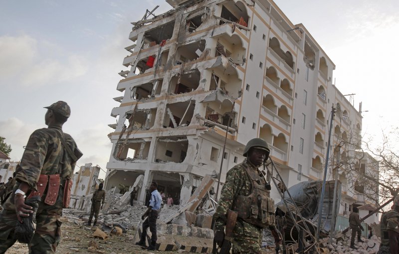 FILE - In this Sunday, July 26, 2015 file photo, an African Union (AU) soldier walks past the scene of destruction following a suicide car bomb attack outside a well-known hotel in the capital Mogadishu, Somalia. The head of the African Union Mission in Somalia (AMISOM) Francisco Caetano Madeira is seeking a surge in troops to help the country's security forces control areas won back from the extremist group al-Shabab. (AP Photo/Farah Abdi Warsameh, File)