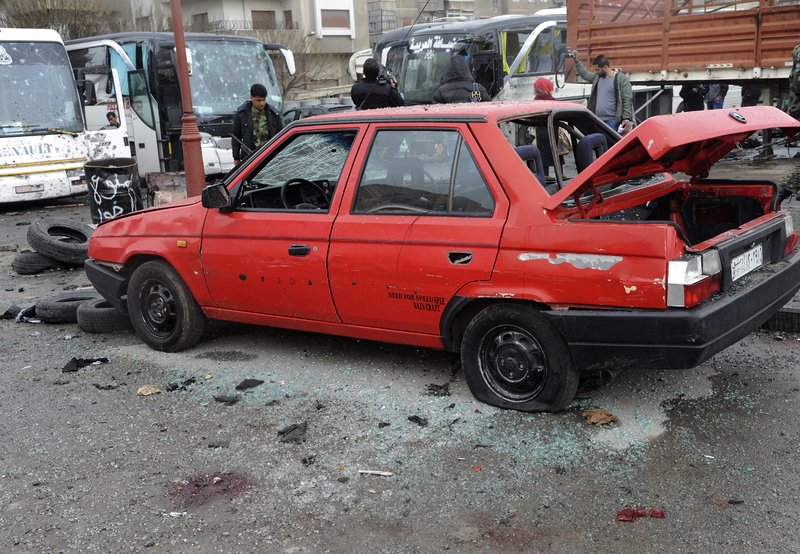 In this photo released by the Syrian official news agency SANA, people inspect the damage to a parking lot at the site of an attack by twin explosions in Damascus, Syria, Saturday, March 11, 2017. Twin explosions Saturday near religious shrines frequented by Shiite pilgrims in the Syrian capital Damascus killed dozens of people, Arab media and activists report. 